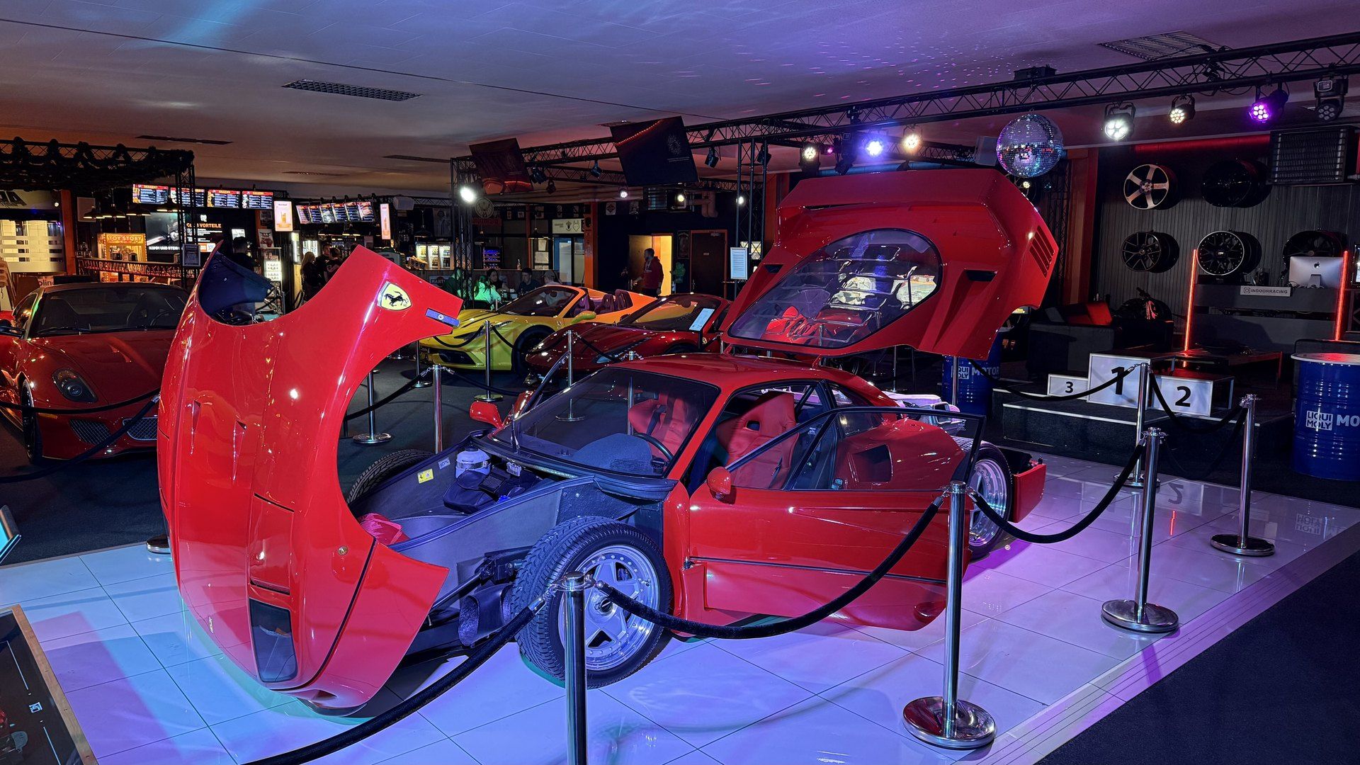Ferrari F40 mit geöffneter Front- und Heckklappe in der Auto-Ausstellung des AP Café INDOOR-RACING Aadorf, dahinter weitere Ferrari und ein Siegerpodest