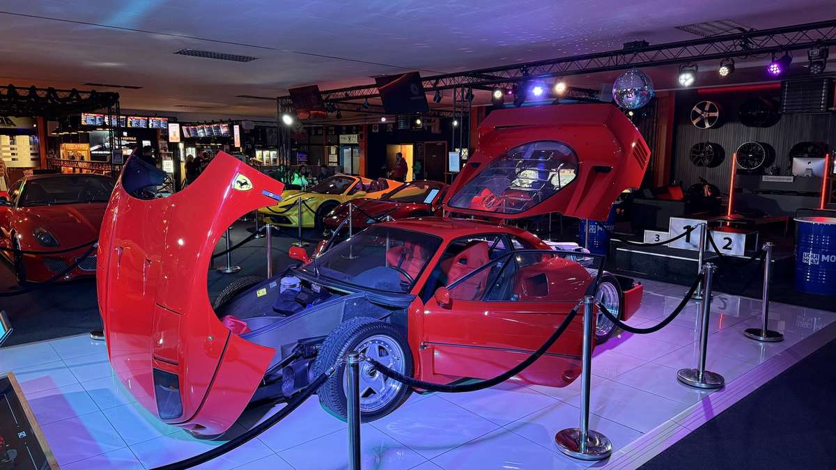 Ferrari F40 mit geöffneter Front- und Heckklappe in der Auto-Ausstellung des AP Café INDOOR-RACING Aadorf, dahinter weitere Ferrari und ein Siegerpodest