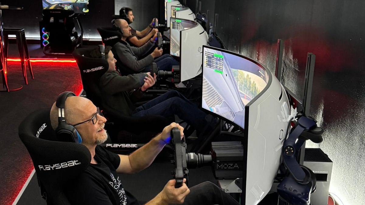 Firmenteam beim Sim-Racing-Event, mehrere Mitarbeitende fahren nebeneinander an Rennsimulatoren
