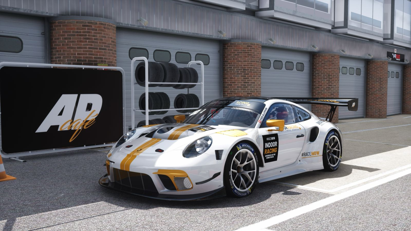 Weiss-goldener Porsche 911 GT3 R mit INDOOR-RACING-Beklebung vor der Boxengasse: geschlossene Garagentore, Reifenregal mit Rennreifen und Werbetafel mit AP-Café-Logo