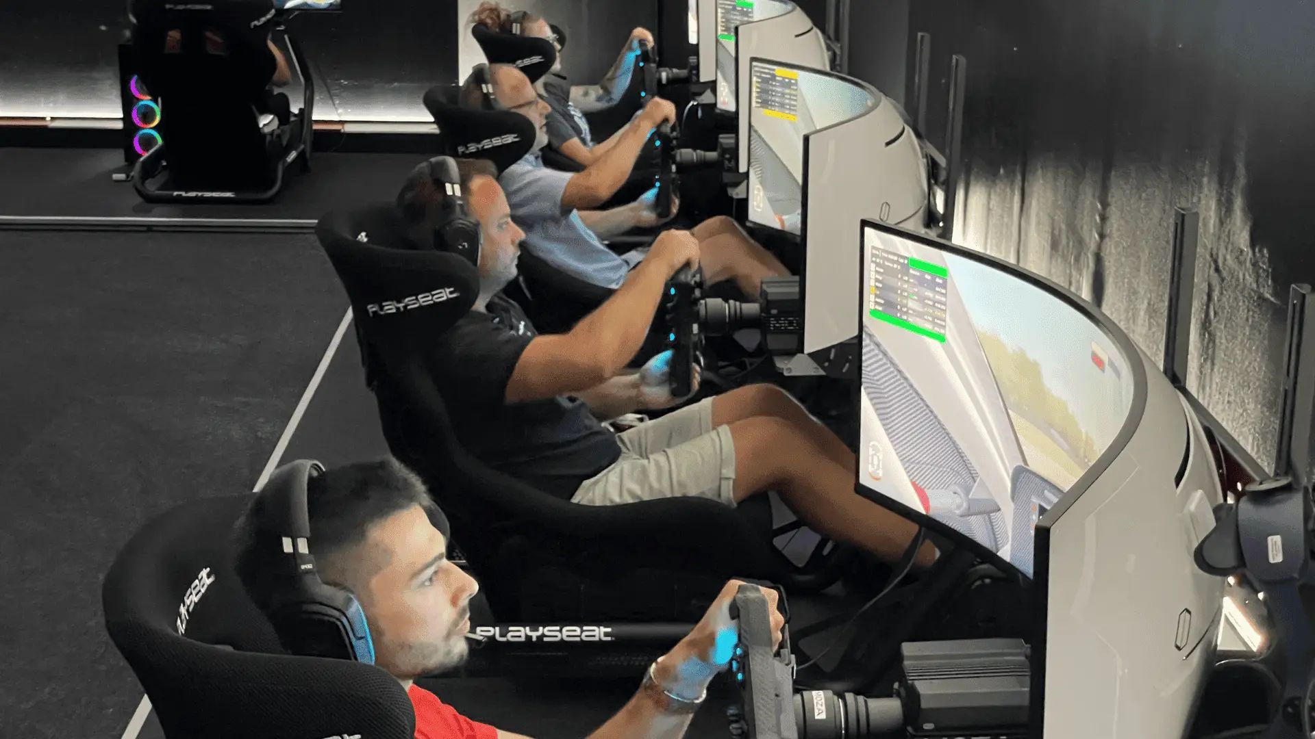 Innenaufnahme des Centers in Aadorf: eine Reihe Playseat-Rennsimulatoren, Fahrer sitzen an den Lenkrädern vor gebogenen Bildschirmen