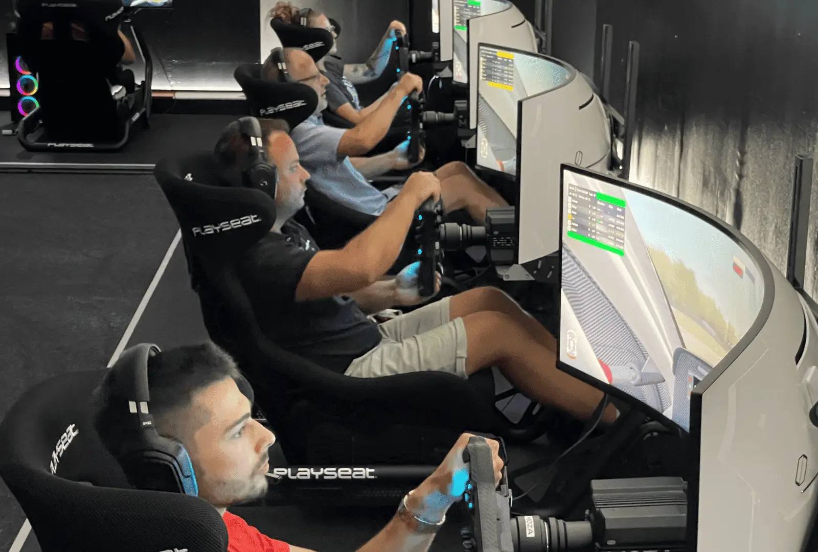 Innenaufnahme des Centers in Aadorf: eine Reihe Playseat-Rennsimulatoren, Fahrer sitzen an den Lenkrädern vor gebogenen Bildschirmen