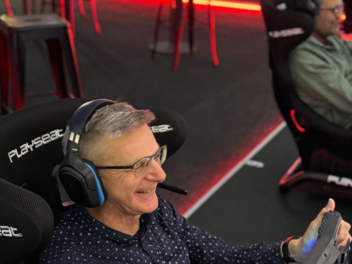 Mann bei seiner ersten Fahrt im Rennsimulator, begeistert am Lenkrad mit Headset