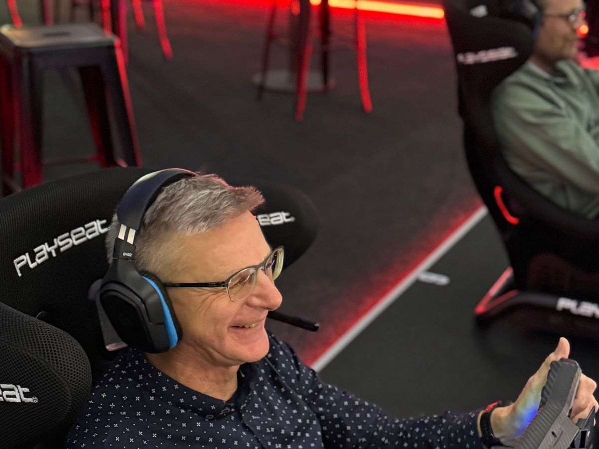 Mann bei seiner ersten Fahrt im Rennsimulator, begeistert am Lenkrad mit Headset