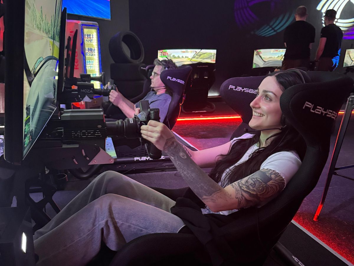 Junge Frau lächelt am Lenkrad eines Rennsimulators beim Sim Racing im AP Café Aadorf
