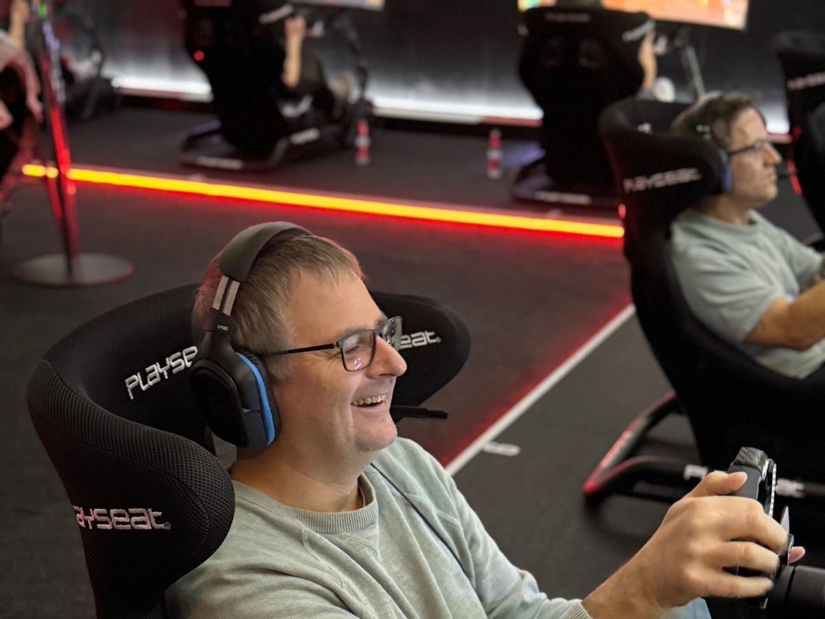 Fahrer lacht begeistert am Lenkrad — der Wow-Moment beim Sim Racing