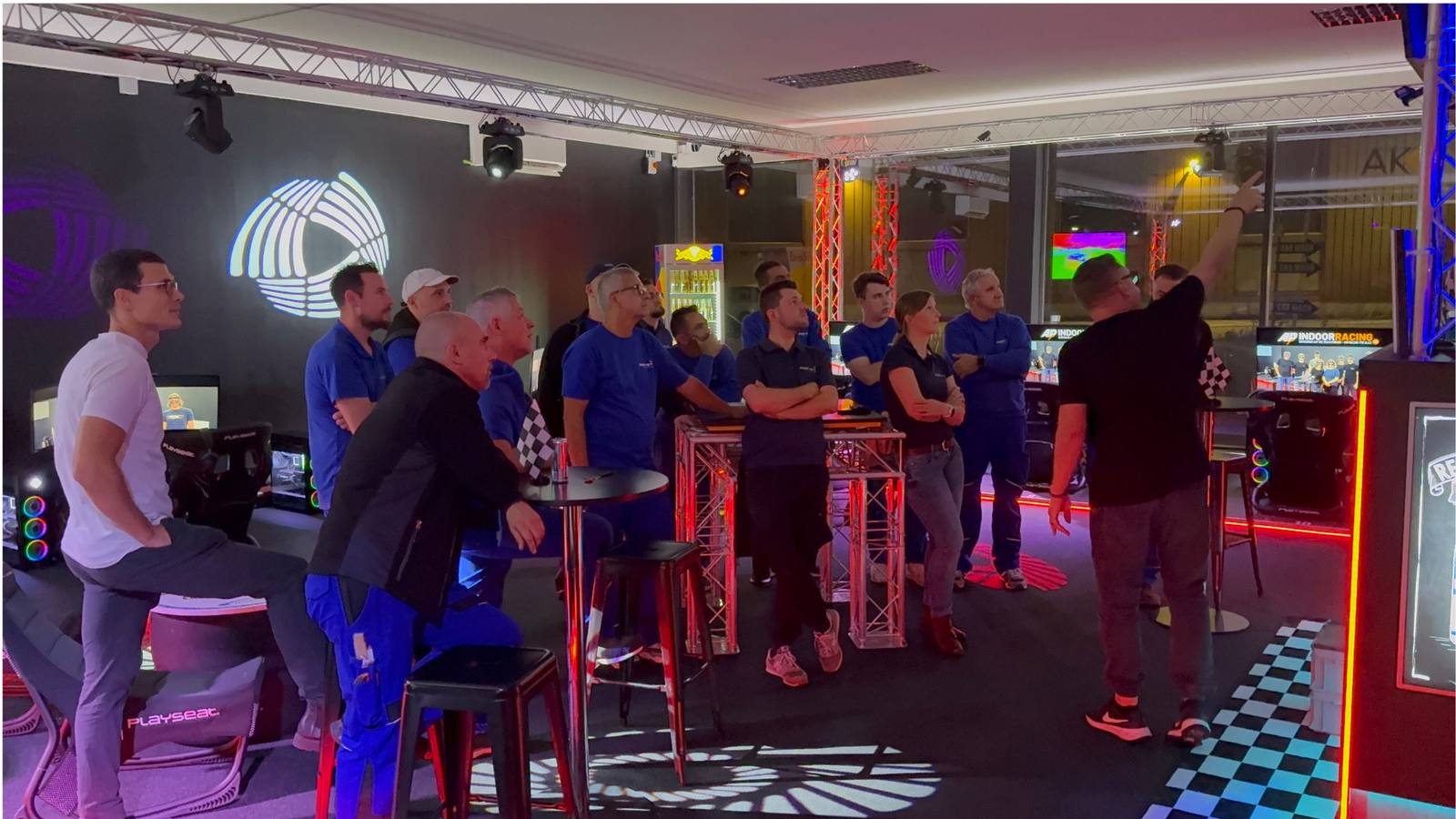 Firmenteam in blauen Poloshirts verfolgt gemeinsam die Rennauswertung im Sim Racing Center Aadorf — Team-Event einer Firma aus Frauenfeld