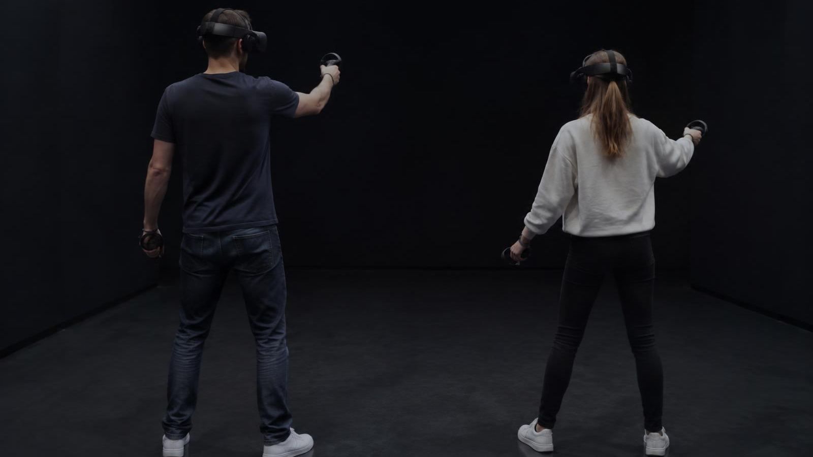 Personen mit VR-Brillen und Controllern in einem leeren Raum (KI-Symbolbild)